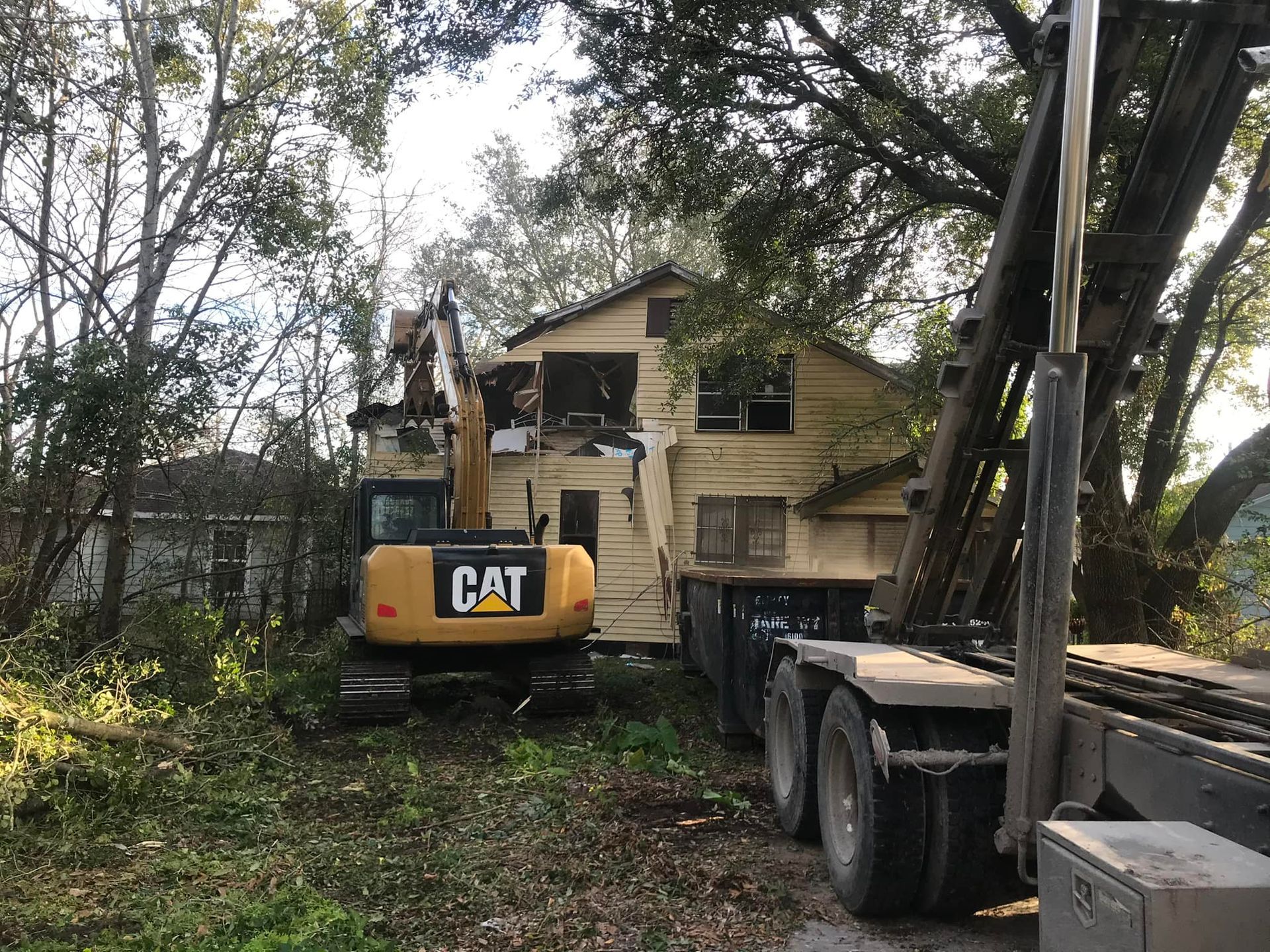 A cat excavator is being used to demolish a house.