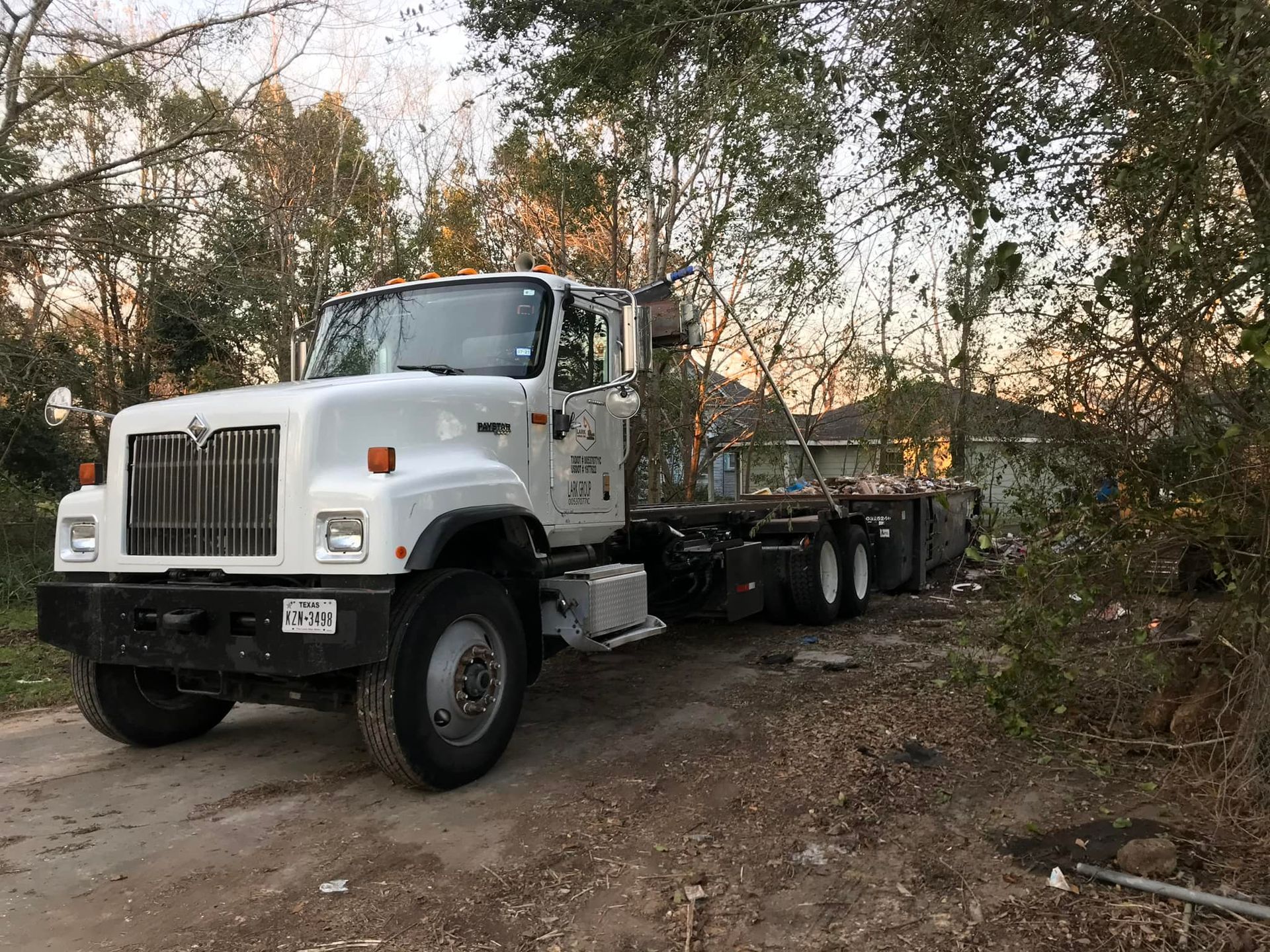 A white semi truck is parked on the side of a dirt road.
