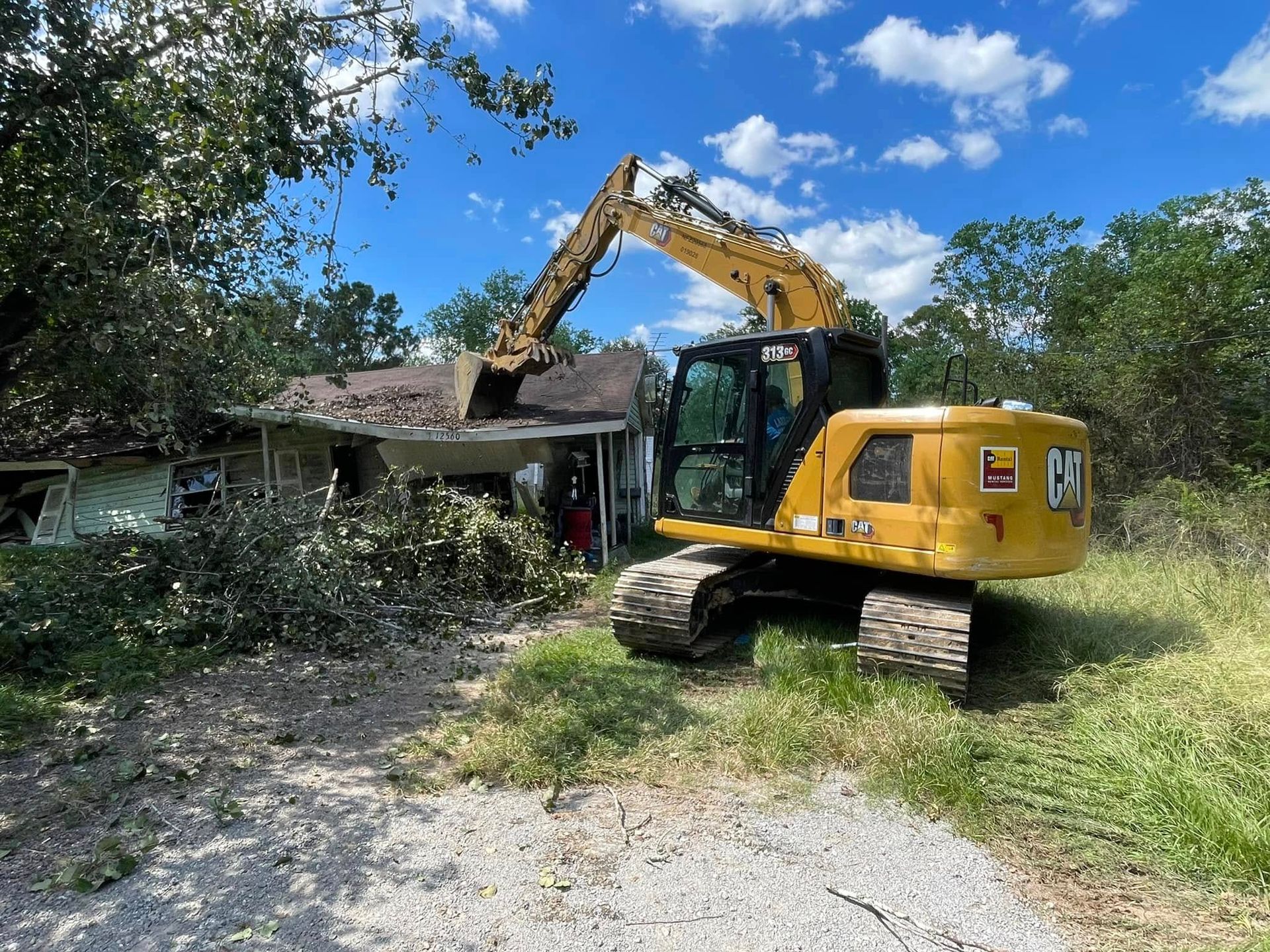A large yellow excavator is demolishing a house.