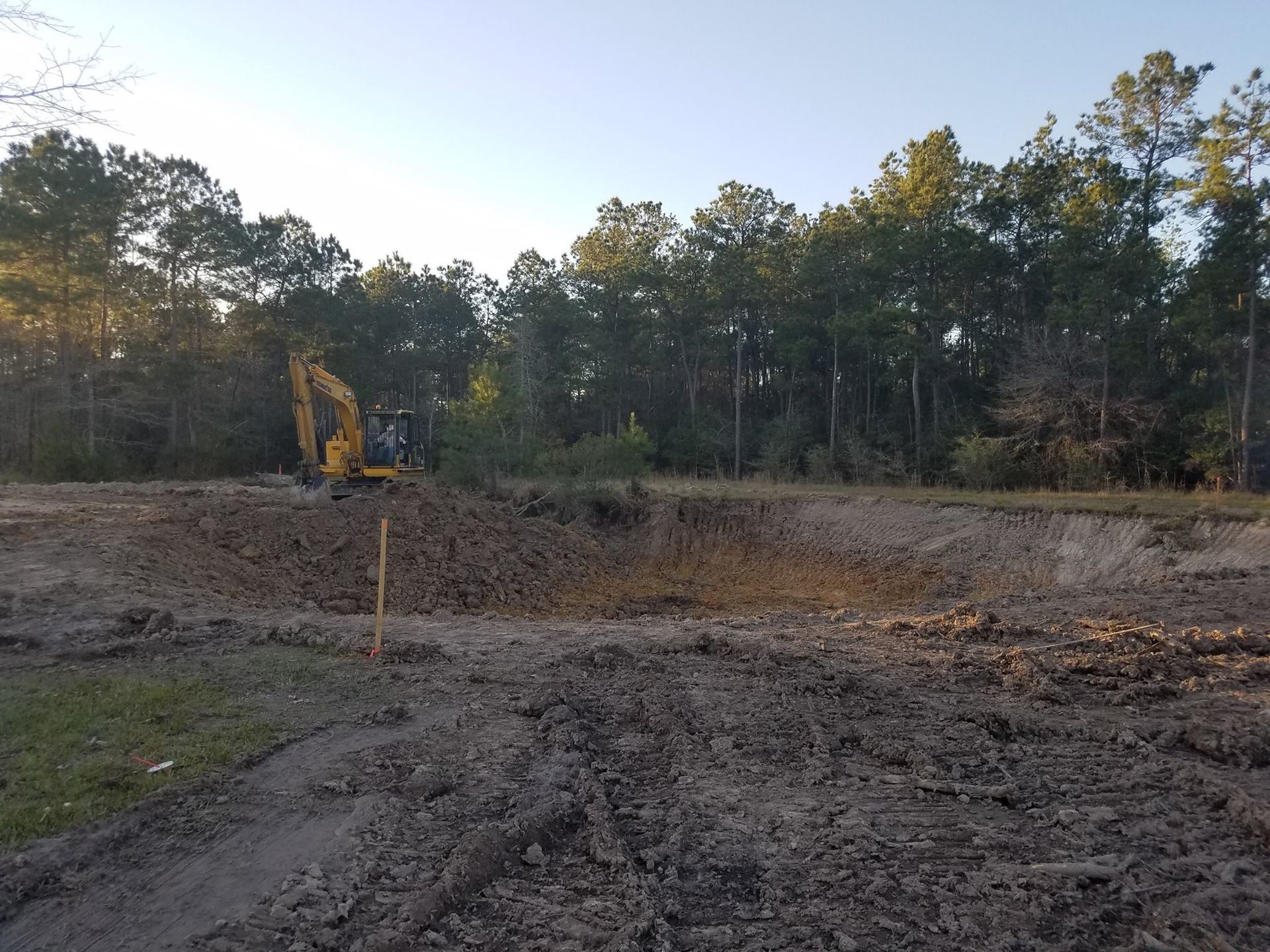 A yellow excavator is sitting on top of a pile of dirt.