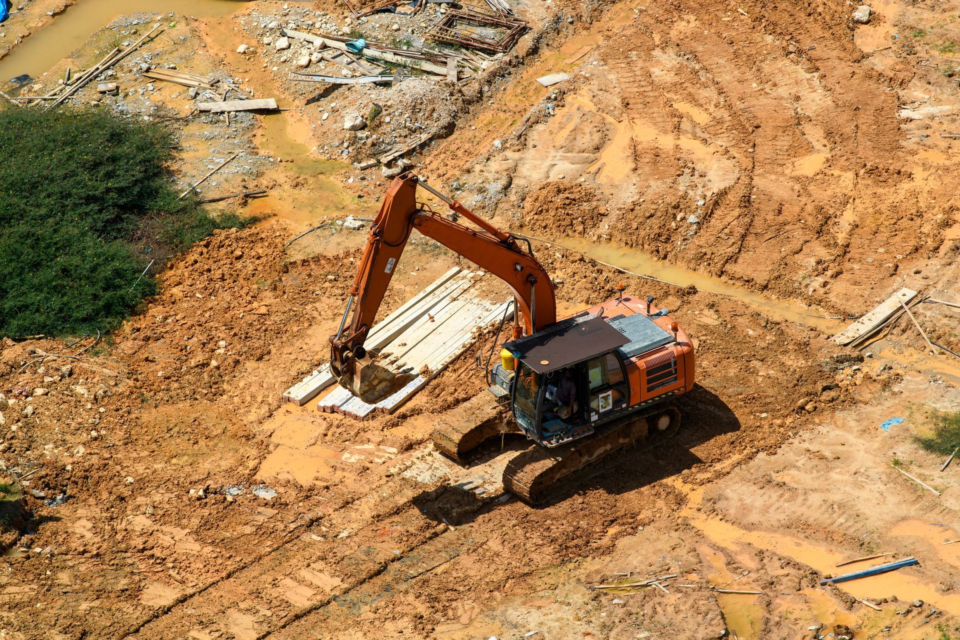 An aerial view of a large excavator digging in a dirt field.