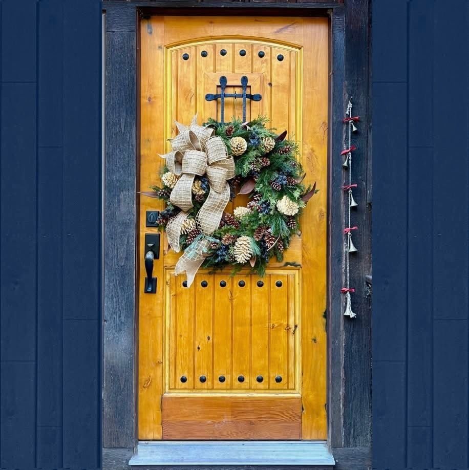 Wooden front door with a festive holiday wreath on a blue house exterior