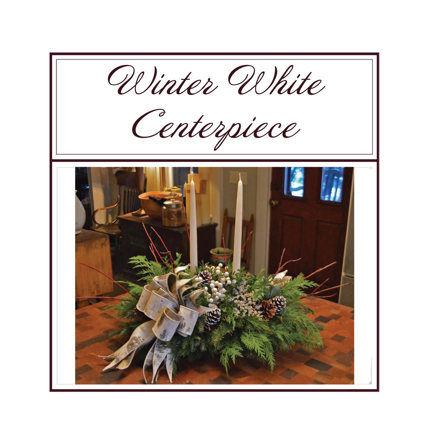 Winter white centerpiece with pine, silver ribbon, and candles on a table.