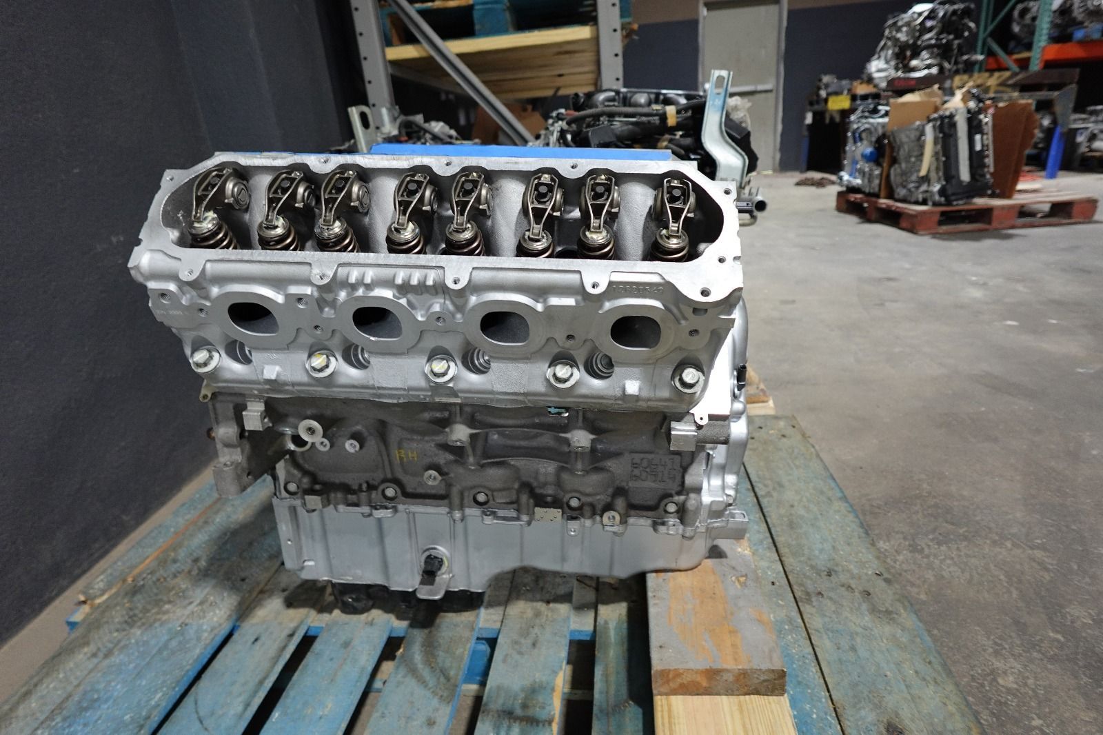 Engine, silver and black, on a wooden pallet in a warehouse setting.