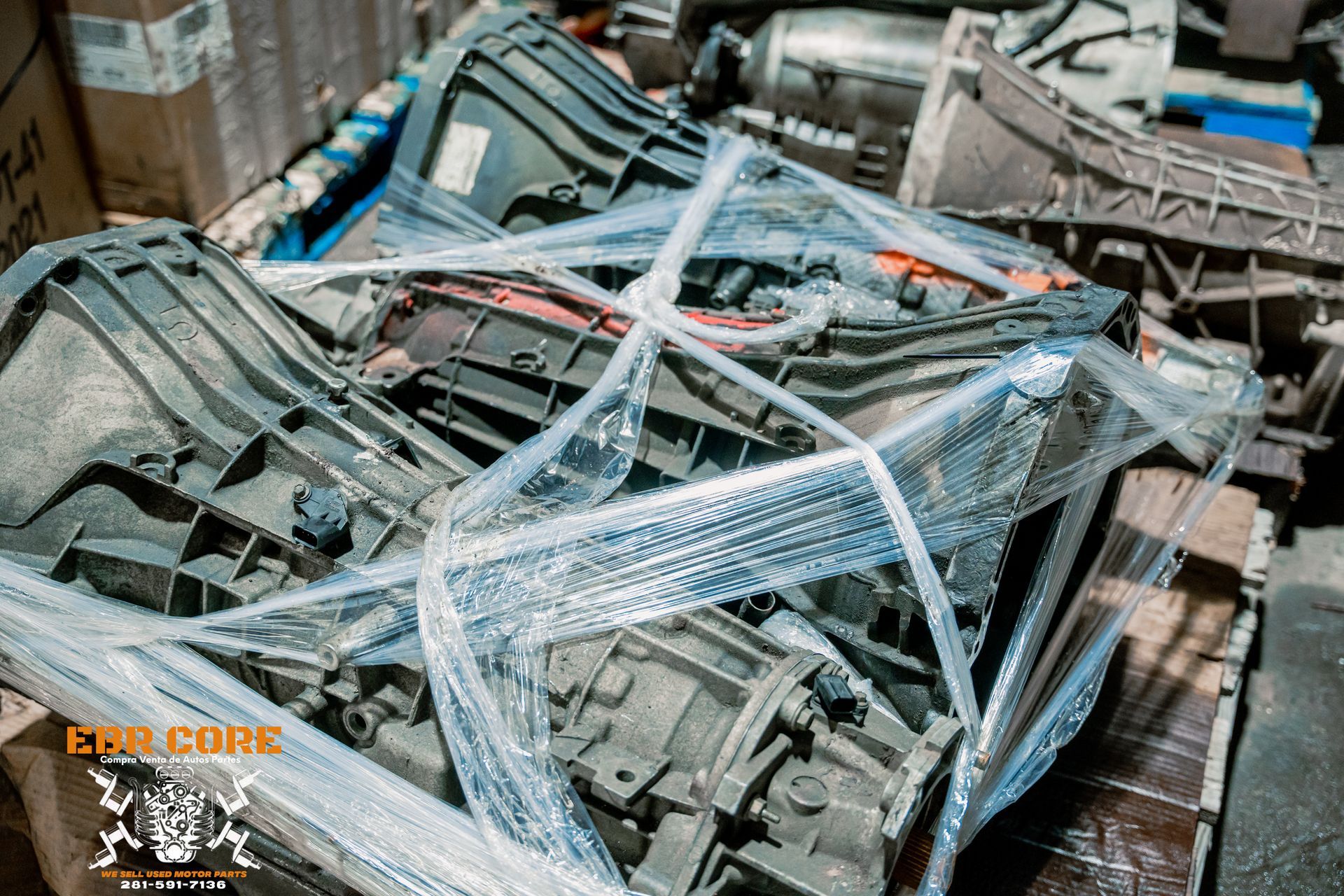 Used automotive transmissions wrapped in plastic, stacked in a warehouse.