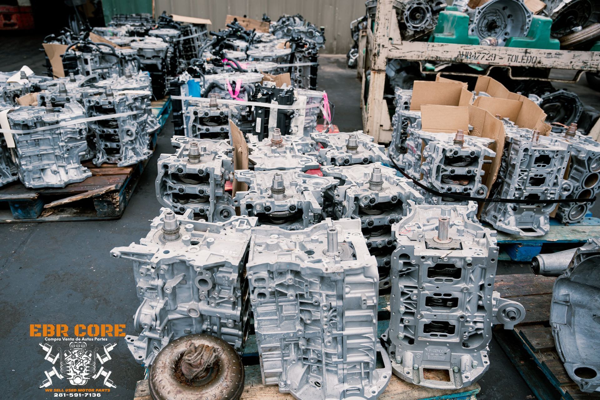 Stacks of metal automotive components in a warehouse setting, some covered in white coating.