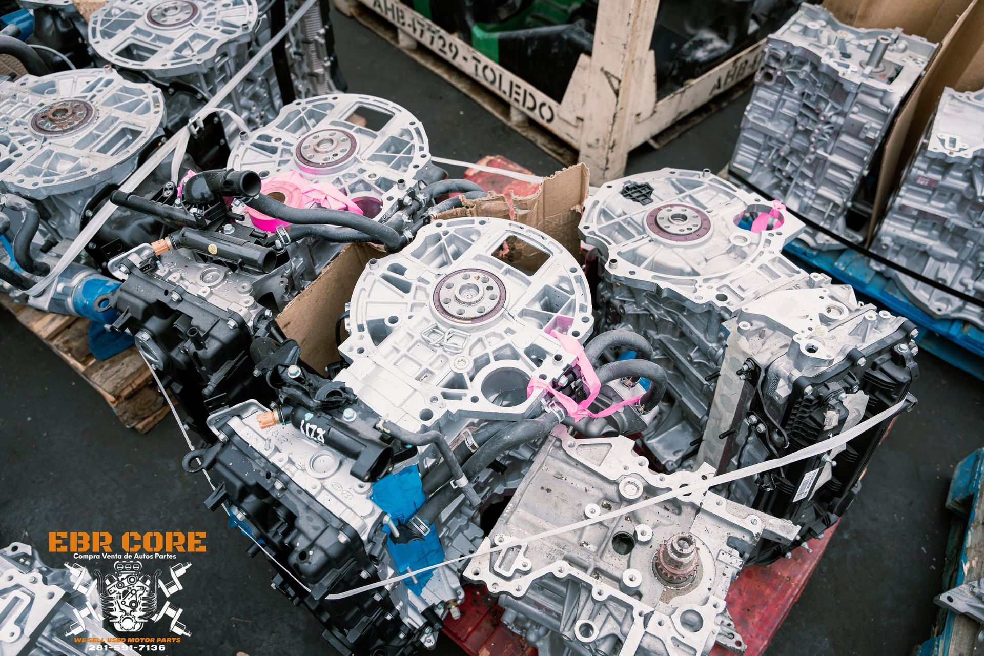 Several disassembled car engines on pallets, machinery parts.