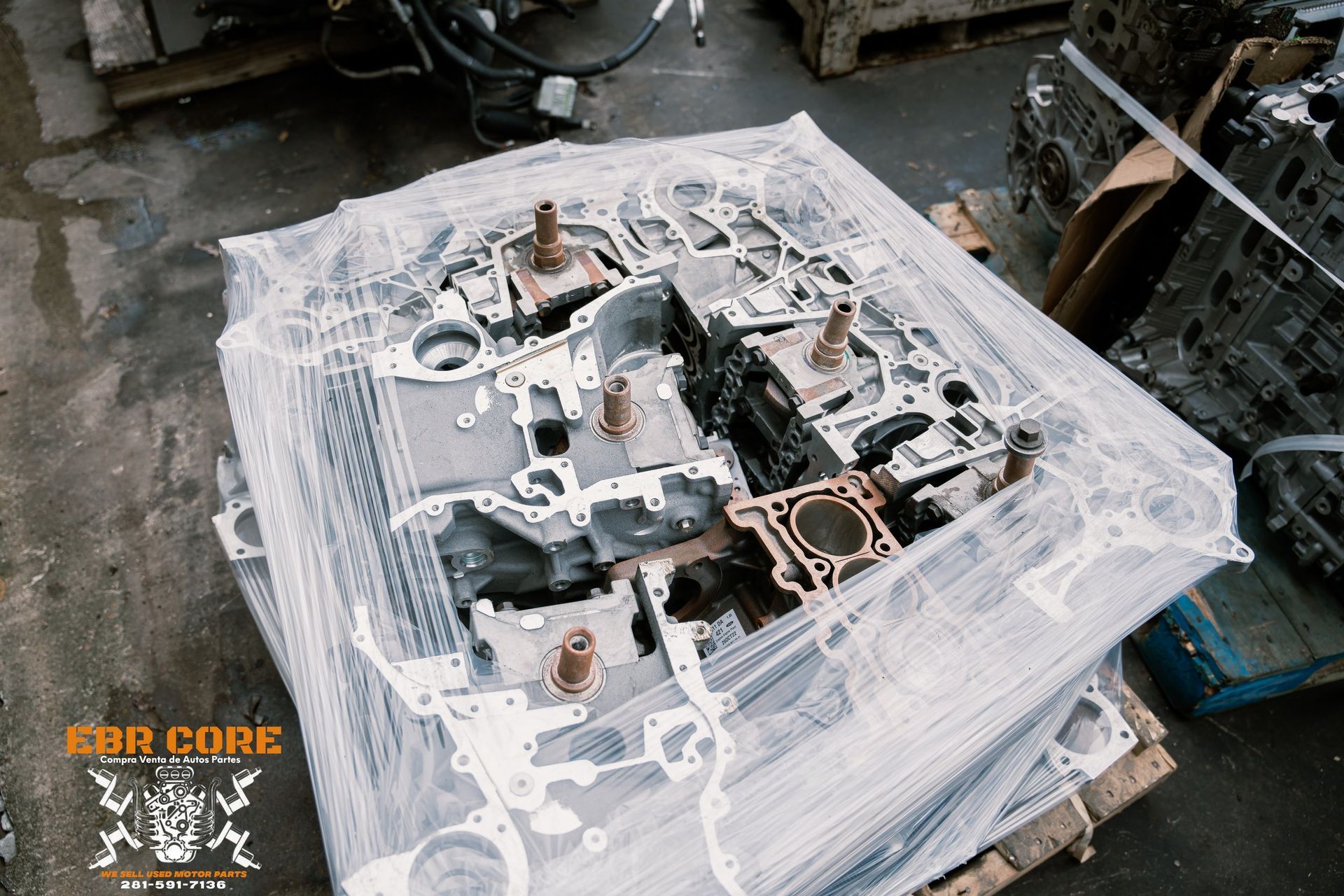 A pallet of disassembled engine parts wrapped in plastic at a warehouse.