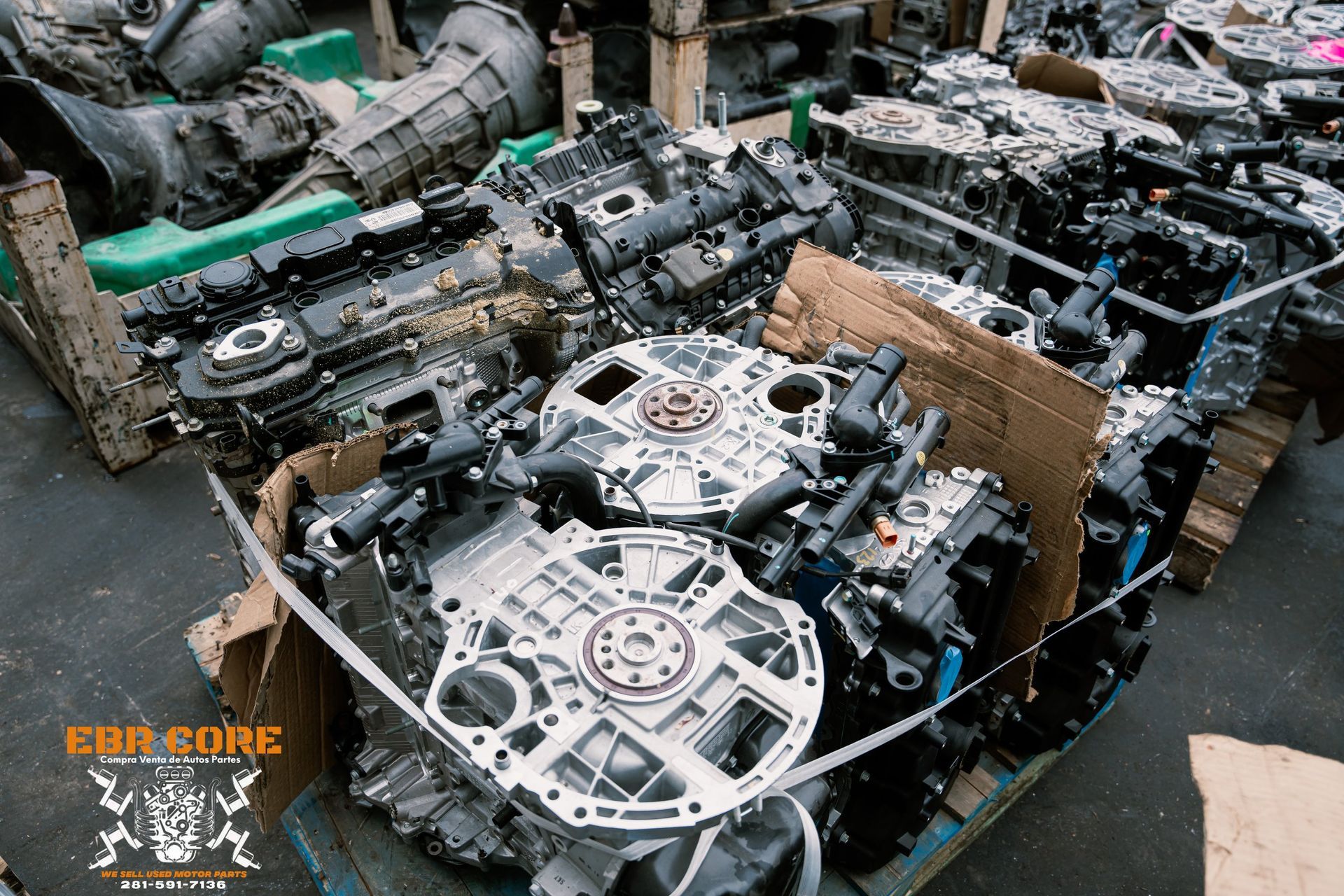 Pile of discarded car engines and parts in a warehouse.