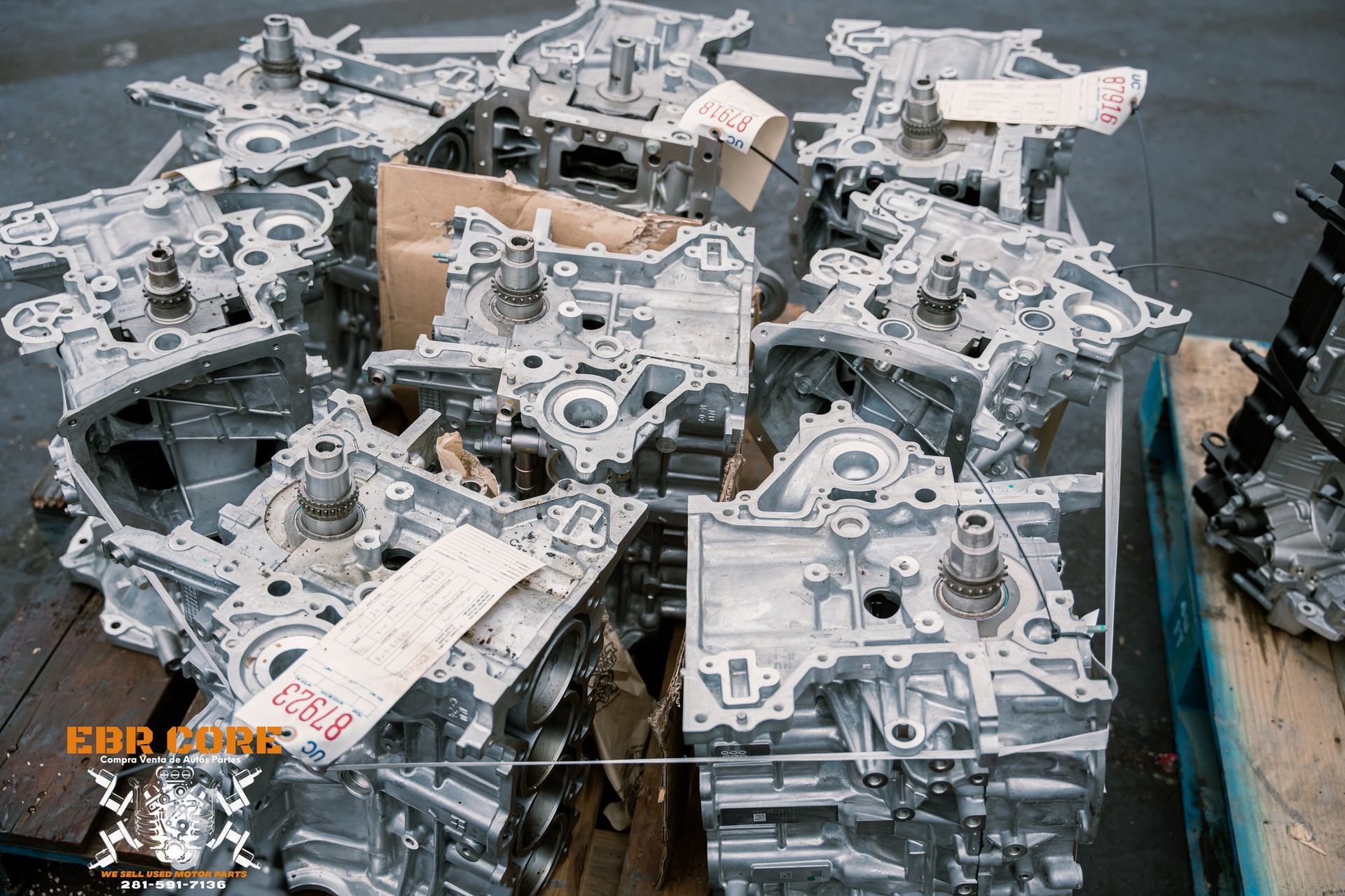 Pile of silver-colored engine blocks, likely cast aluminum, on a pallet; an industrial setting.