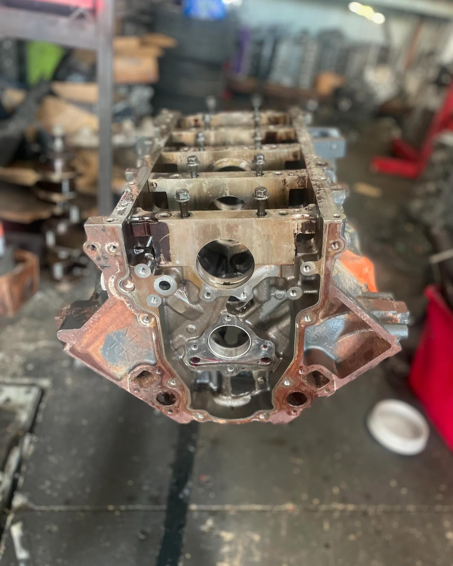 Engine block with rusted exterior, viewed from the top, in a workshop setting.