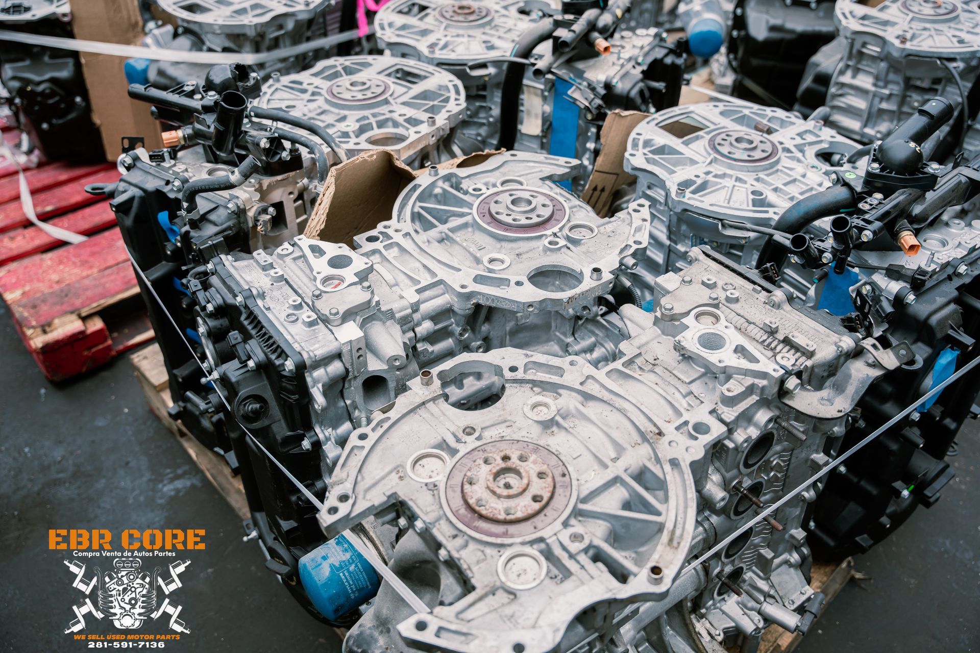 Several silver car engines stacked on a wooden pallet, close-up shot.