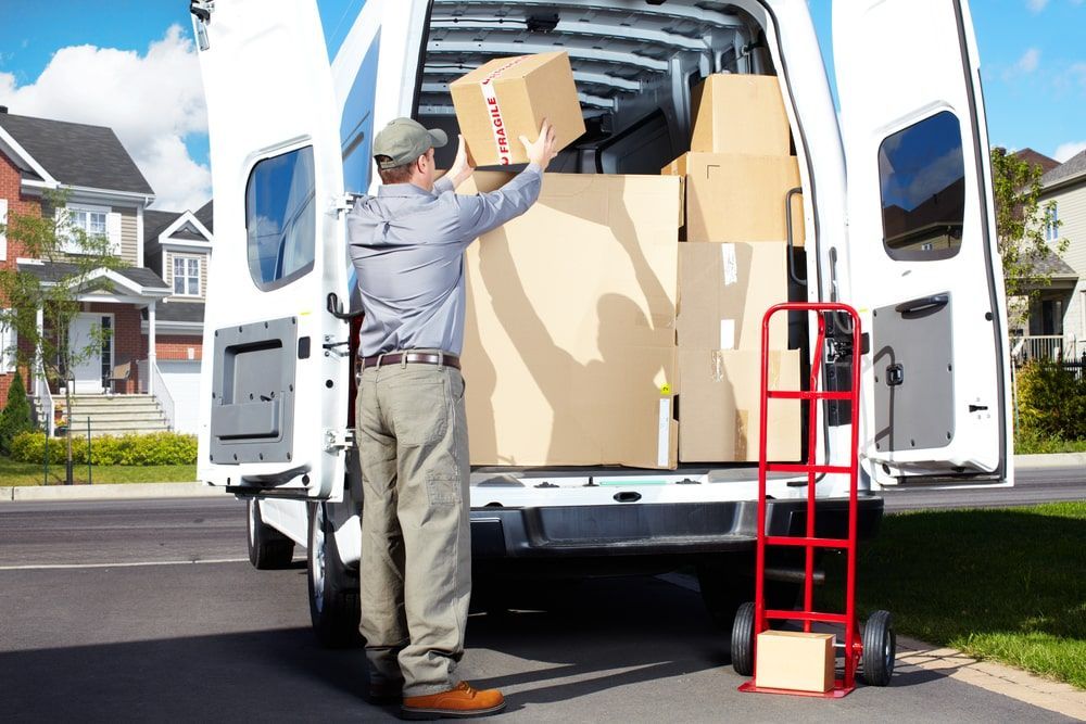 A Delivery Man Is Loading Boxes Into A White Van — Greater Newcastle Removals In Rathmines, NSW