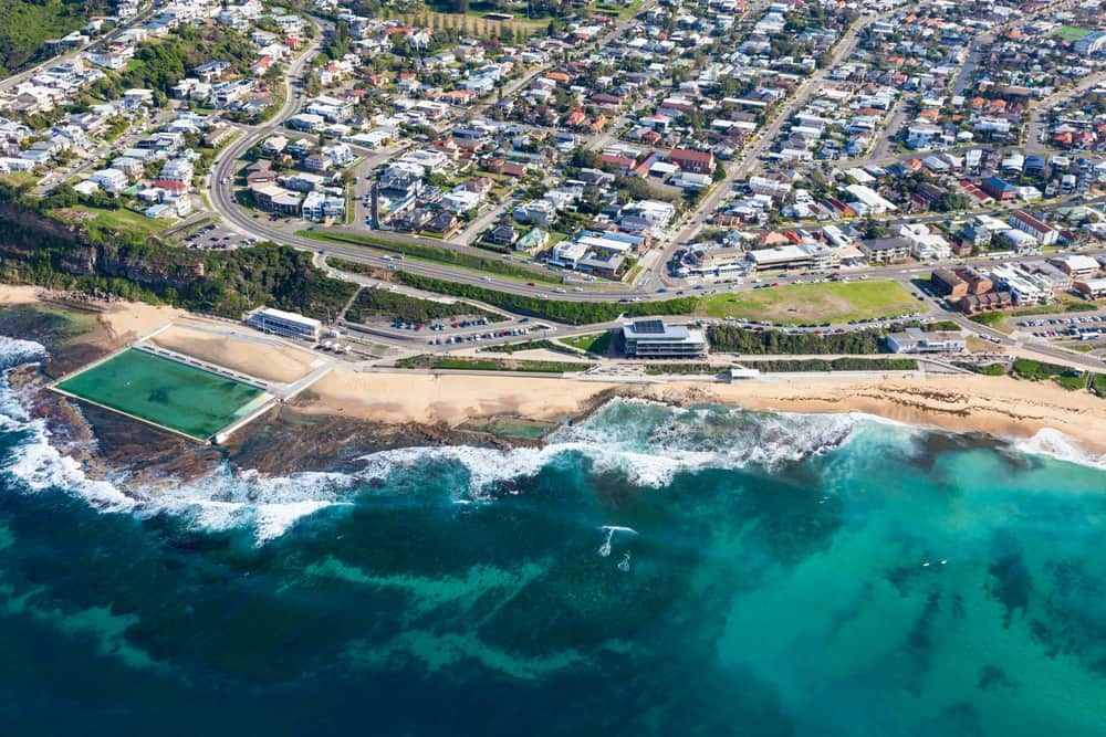 An Aerial View of A Beach with A Swimming Pool and A City in The Background — Greater Newcastle Removals In Merewether, NSW
