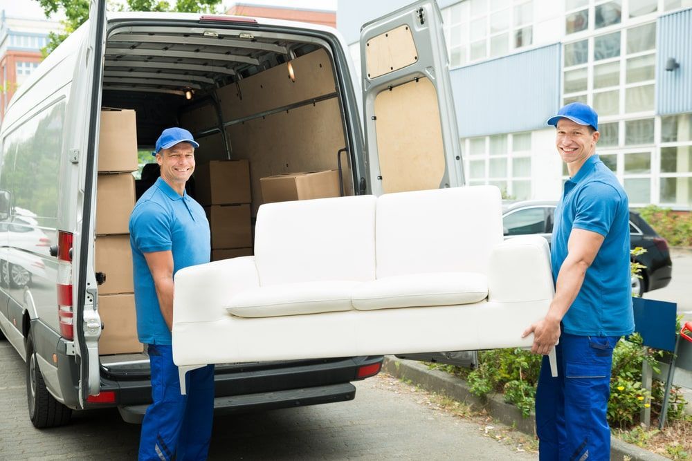 Two Men Are Carrying A White Couch Out Of A Van  — Greater Newcastle Removals In Rathmines, NSW