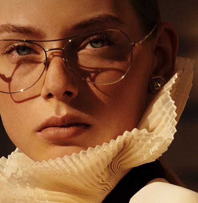 A close up of a woman wearing glasses and a pleated collar