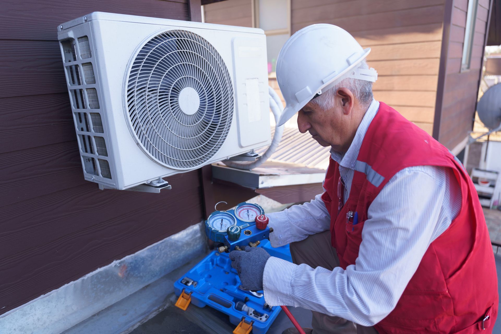 A senior HVAC technician is checking unit pressure during a routine HVAC repair service.