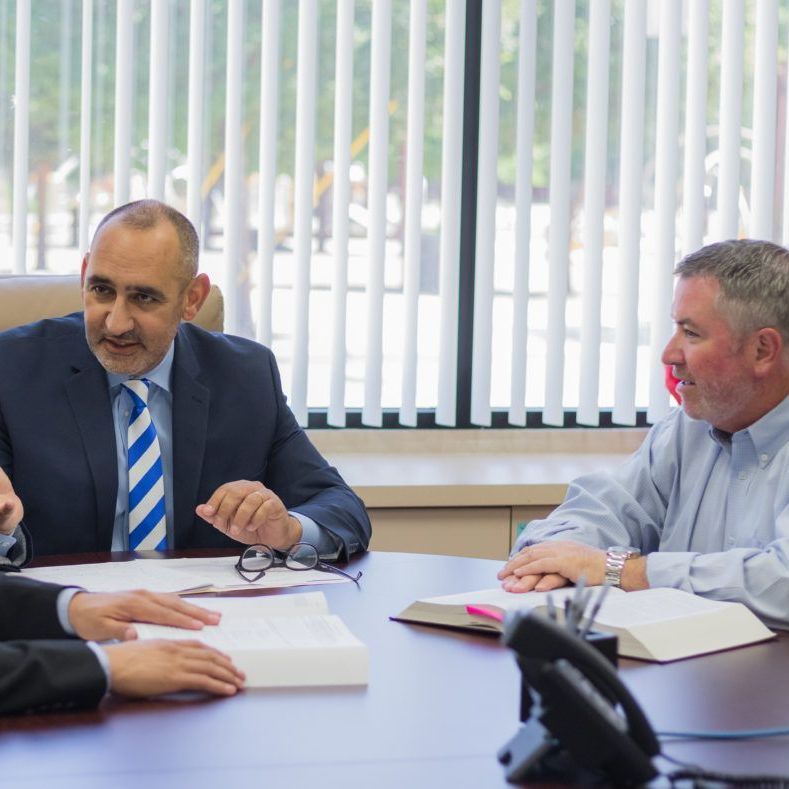 A group of men are sitting at a table having a meeting.