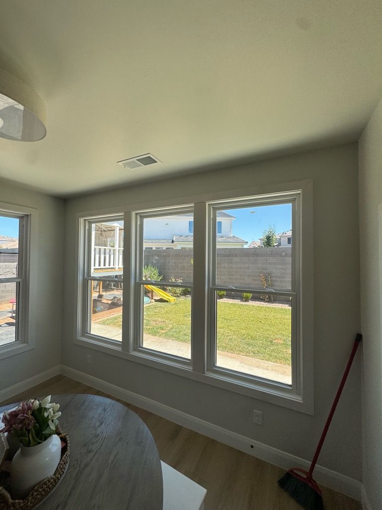 Bright sunroom with large windows, yard view, and a red broom leaning in the corner.