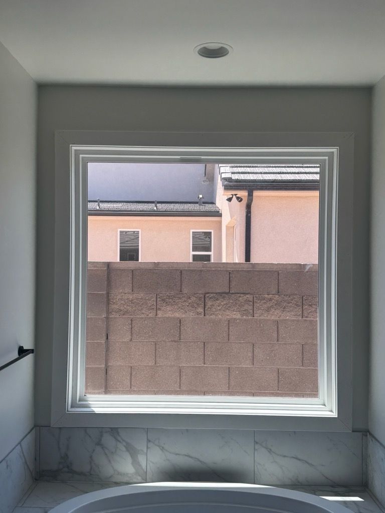 Empty room with a large window looking out to a block wall and neighboring building
