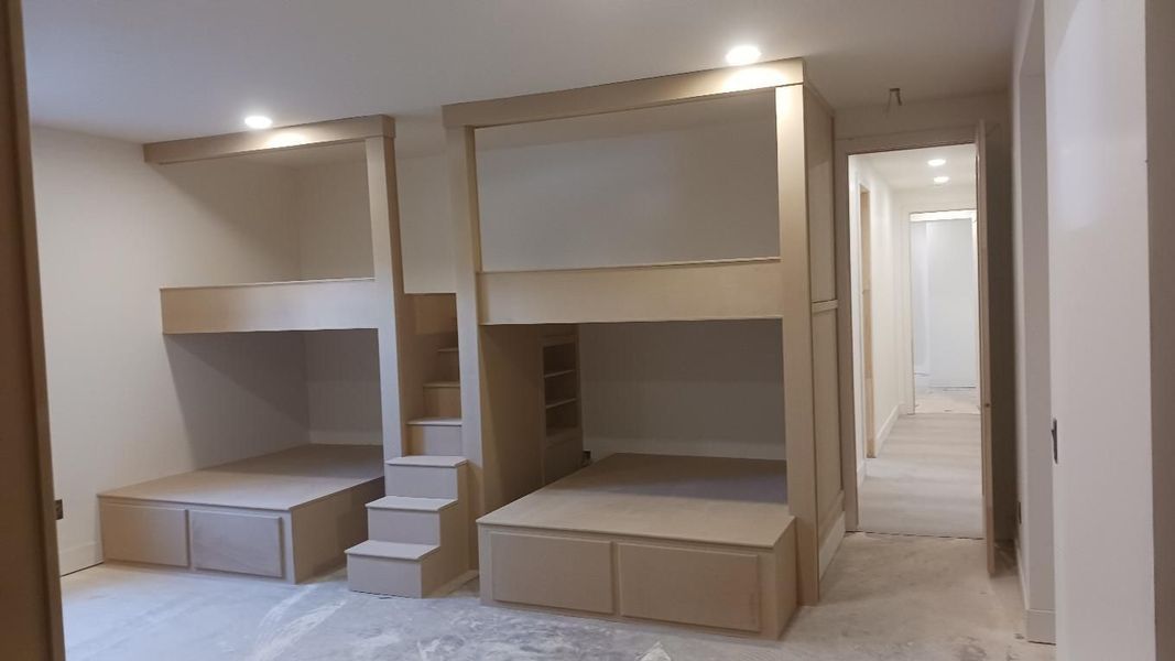 Two-tone bunk beds with stairs in a neutral-colored bedroom.