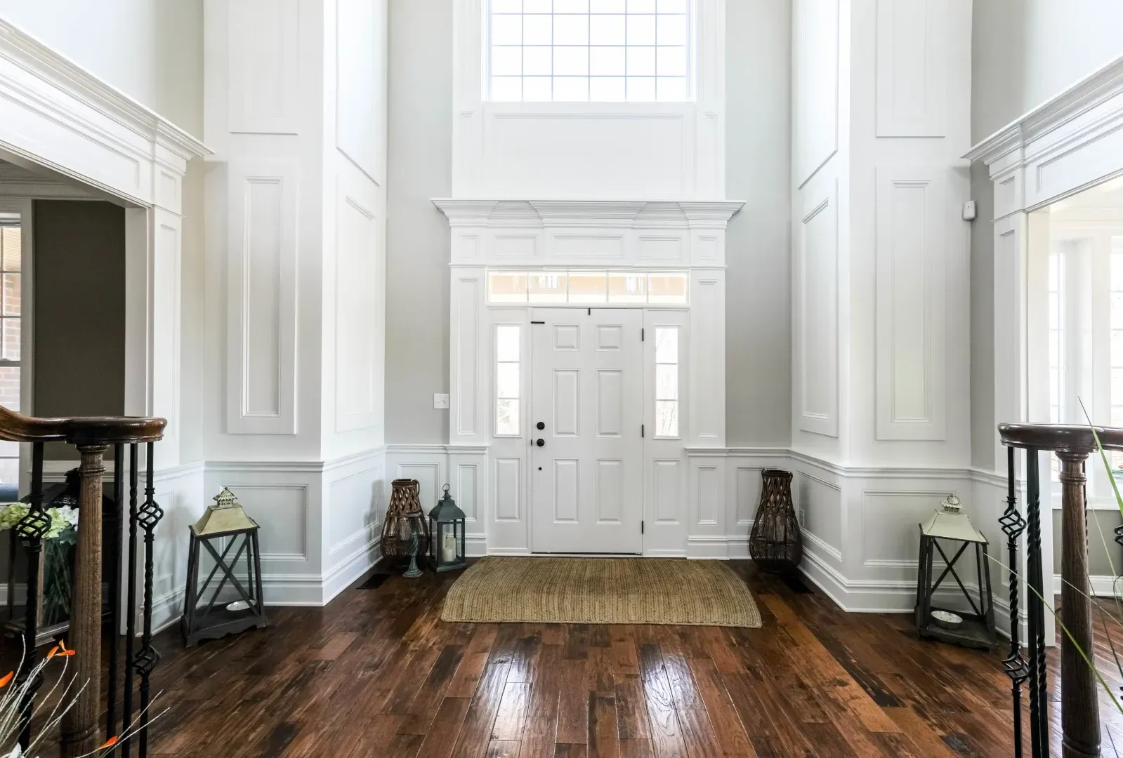 Grand entrance hall with white trim, dark wood floor, and a front door.