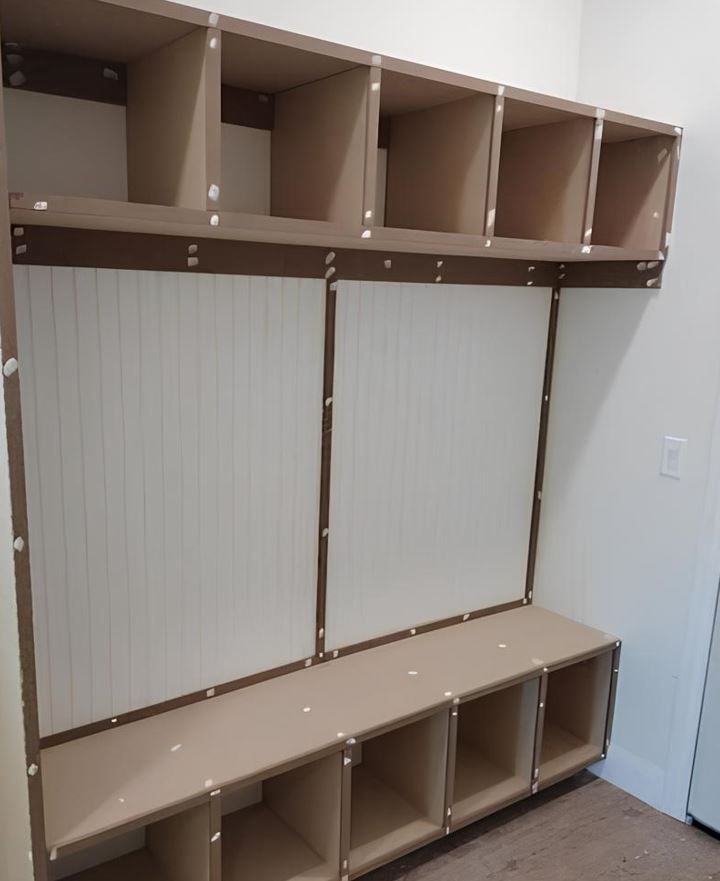 Built-in mudroom storage with beige cubbies, a bench, and white paneling.