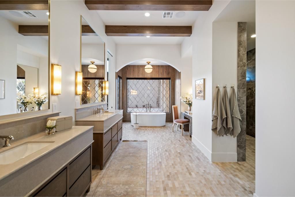 Luxurious bathroom with double sinks, tub, and wooden beams.