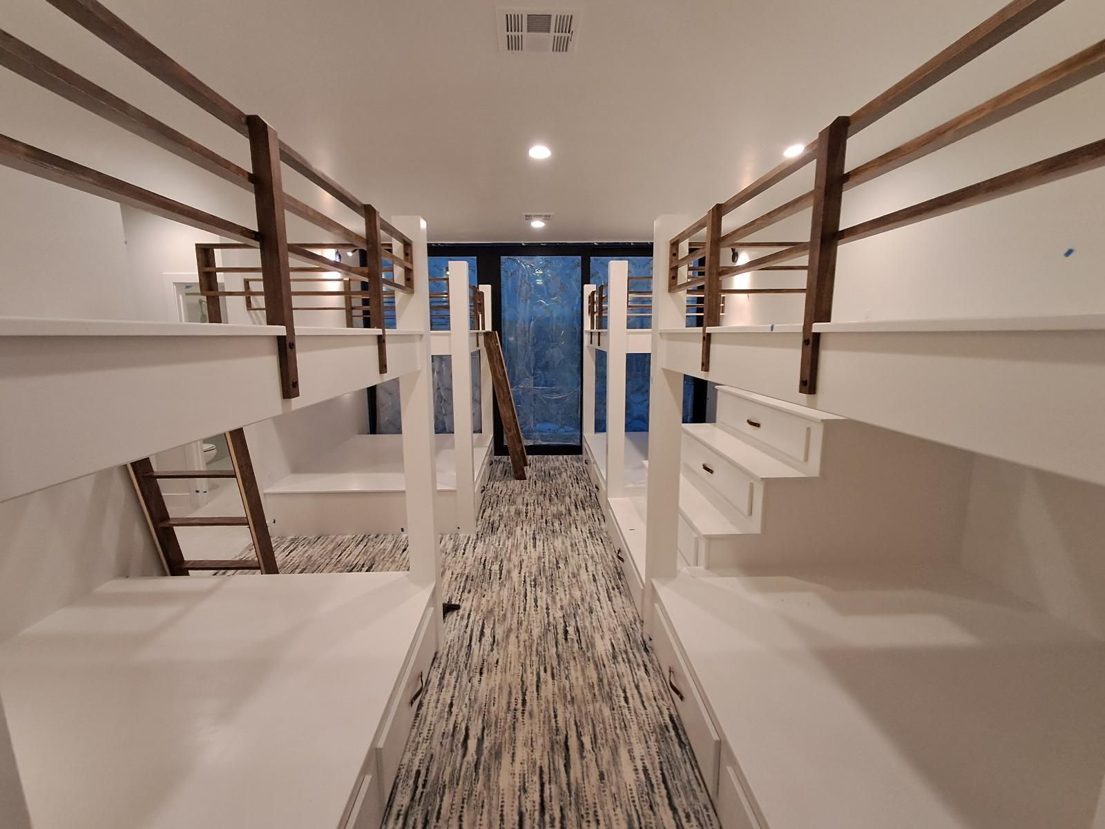 Interior view of a room with two sets of bunk beds, white with wooden accents.