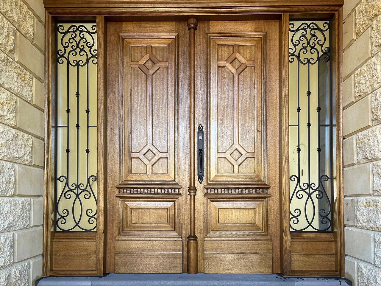 Ornate wooden double front doors with decorative ironwork on either side