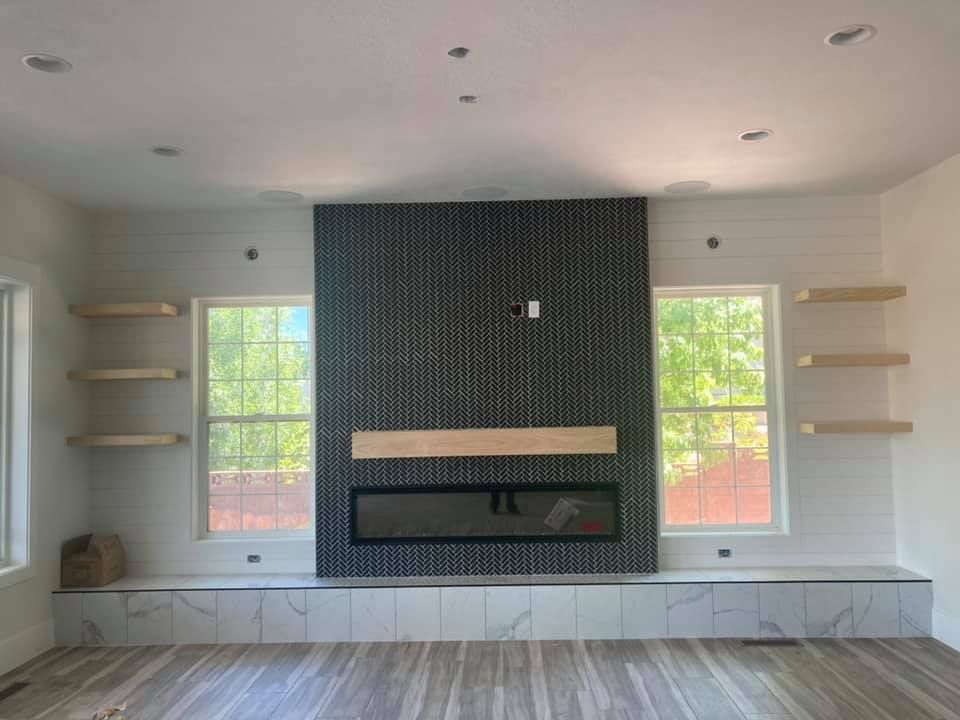 Modern living room with a black-tiled fireplace, built-in shelves, and two windows