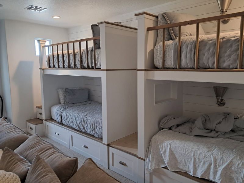 Bunk beds built into a white-paneled wall, with storage drawers and wooden railings.