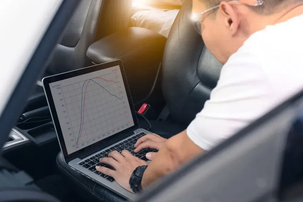 Man in Car Using Laptop, Likely for Car Diagnostics — Advanced Auto Electrics & Mechanical in Innisfail, QLD