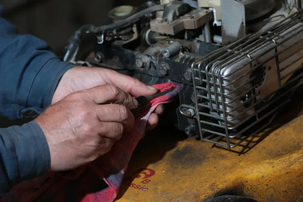 Hands Wiping an Engine Component With a Red Cloth — Advanced Auto Electrics & Mechanical in Innisfail, QLD
