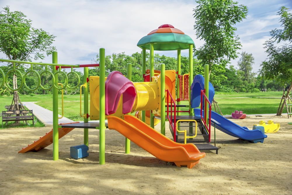 A Colourful Playground Set In A Park With Trees In The Background — Envy Landscape Supplies In Urangan, QLD