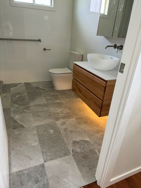 Bathroom With Gray Tiled Floor, White Walls, Wooden Vanity — Red Emperor Constructions in Cannonvale, QLD