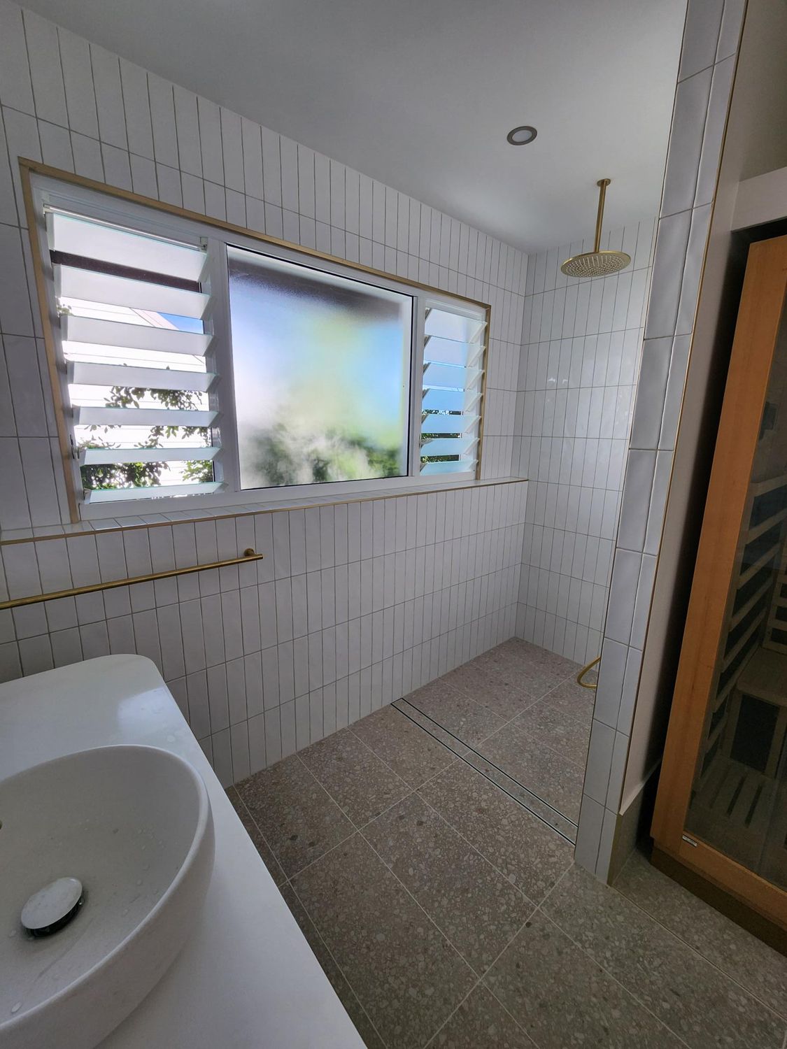 Bathroom With White Tiled Walls, Window, Sink, Shower, and Brown Door — Red Emperor Constructions in Cannonvale, QLD