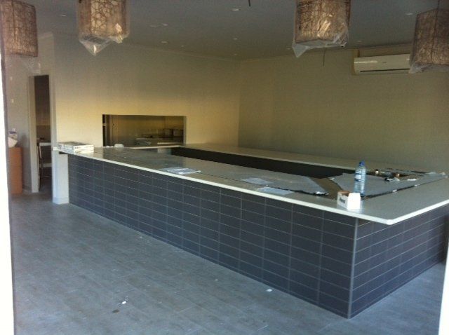 A kitchen with a long counter and a few lamps hanging from the ceiling — Red Emperor Constructions in Cannonvale, QLD