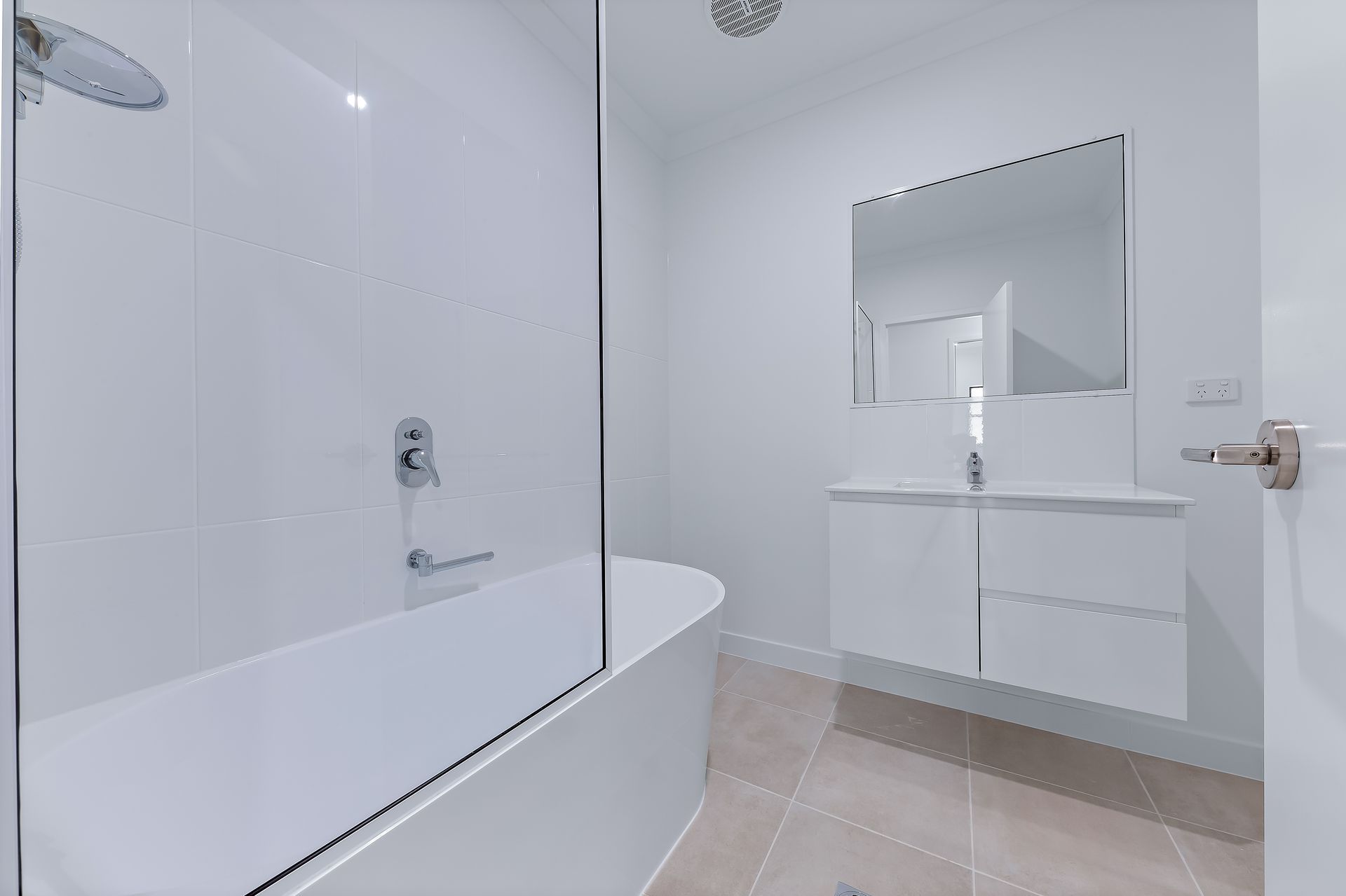 White Bathroom With a Bathtub, Shower, Vanity, and a Mirror — Red Emperor Constructions in Cannonvale, QLD