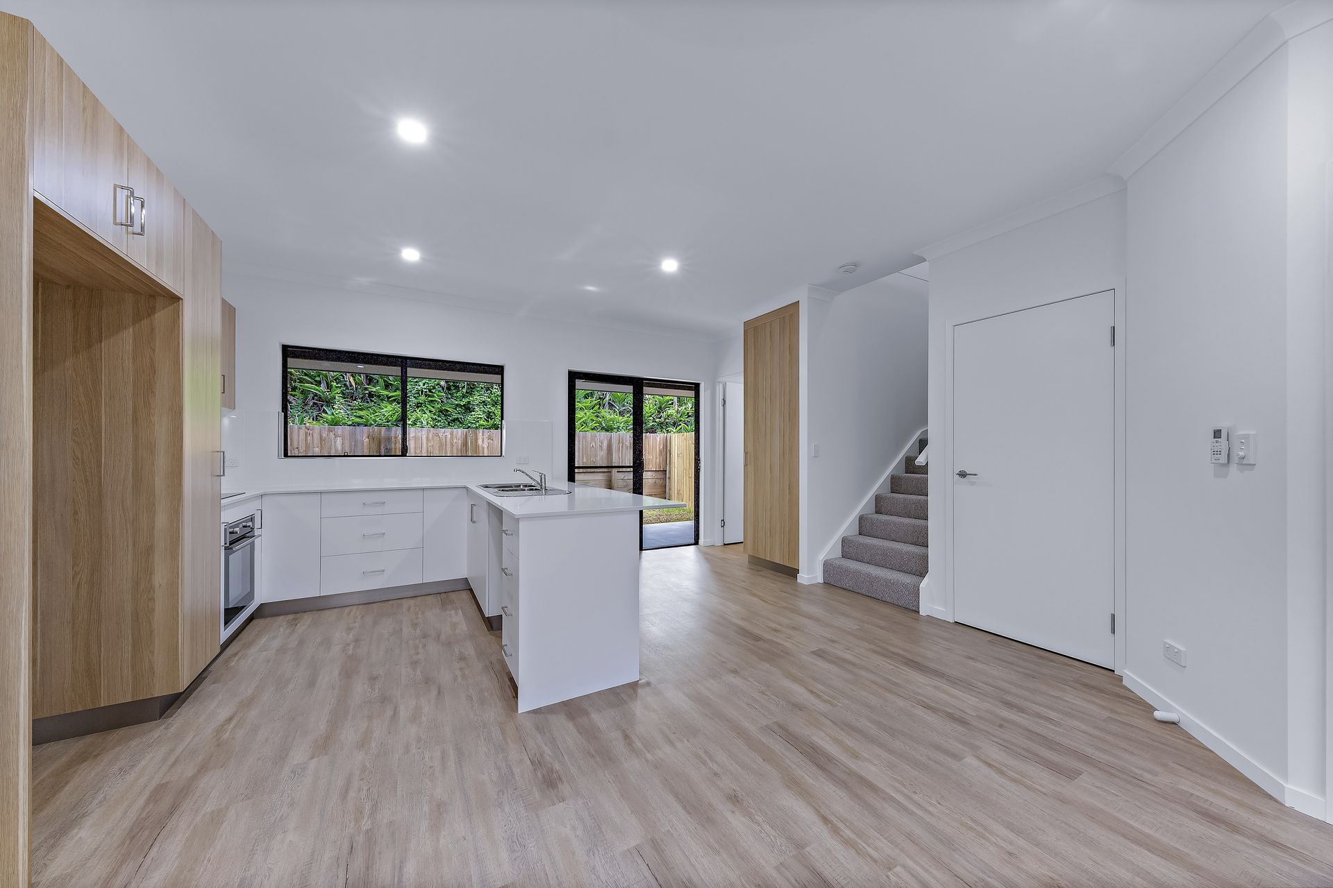 Modern Kitchen With White Cabinets, Island, Wooden Accents — Red Emperor Constructions in Cannonvale, QLD
