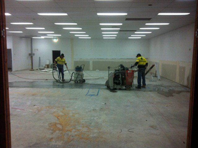 Two men are working in a large empty room — Red Emperor Constructions in Cannonvale, QLD