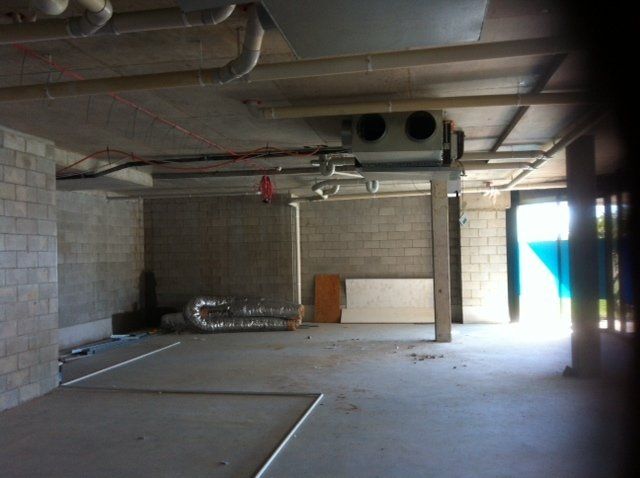 An empty room with pipes hanging from the ceiling — Red Emperor Constructions in Cannonvale, QLD