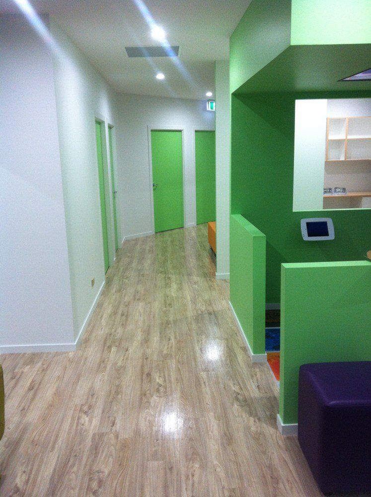 A hallway with wooden floors and green walls — Red Emperor Constructions in Cannonvale, QLD