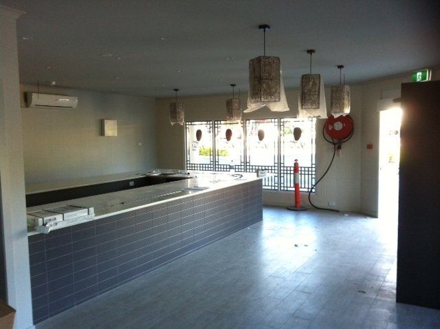 An empty room with a fire extinguisher on the wall — Red Emperor Constructions in Cannonvale, QLD