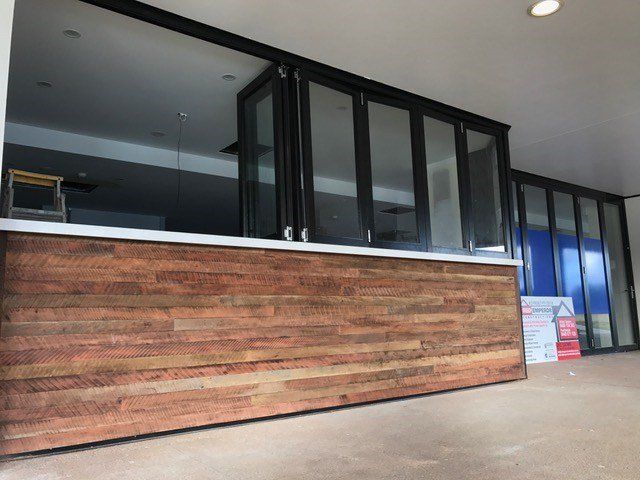 A room with a wooden wall and lots of windows — Red Emperor Constructions in Cannonvale, QLD