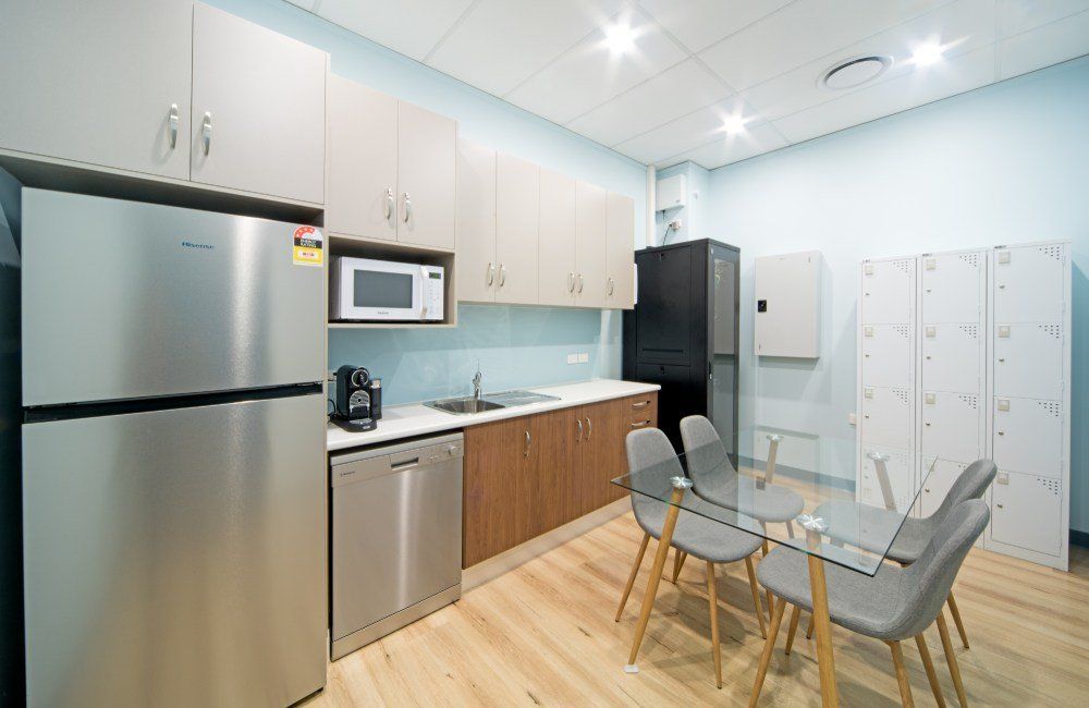 A kitchen with stainless steel appliances , a table and chairs— Red Emperor Constructions in Cannonvale, QLD