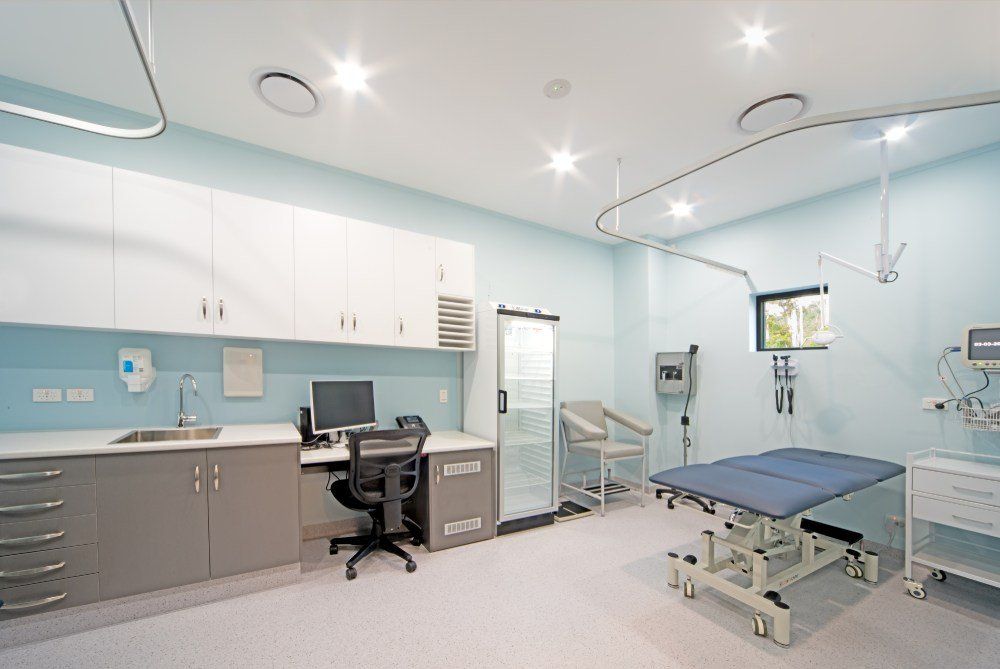 A hospital room with a bed , desk , chair and computer — Red Emperor Constructions in Cannonvale, QLD