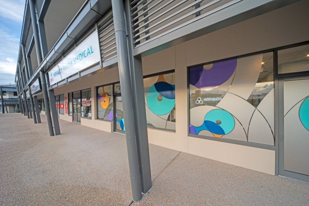 A building with a lot of windows and a sign that says ' optical ' on it — Red Emperor Constructions in Cannonvale, QLD