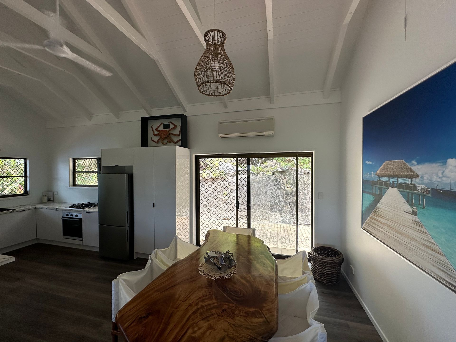 White Interior With Wooden Dining Table, Sliding Doors to a View, Artwork — Red Emperor Constructions in Cannonvale, QLD