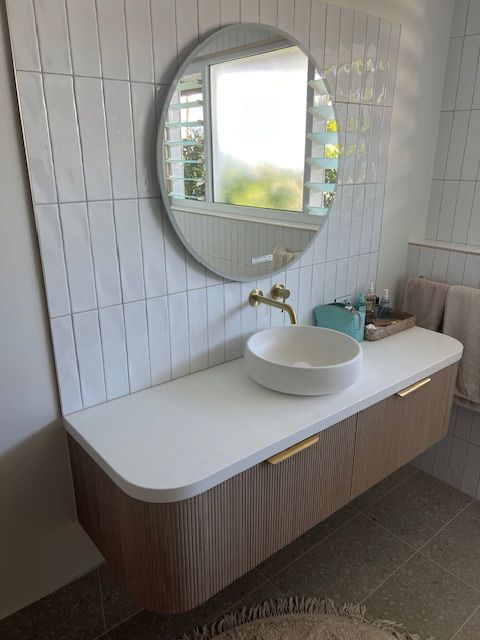 Bathroom Vanity With White Countertop, Round Mirror and Vessel Sink — Red Emperor Constructions in Cannonvale, QLD